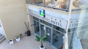 Het uiterlijk van Hotel Alcocebre Suites, met een duidelijke ingang, plantenpotten en een zichtbare trap.