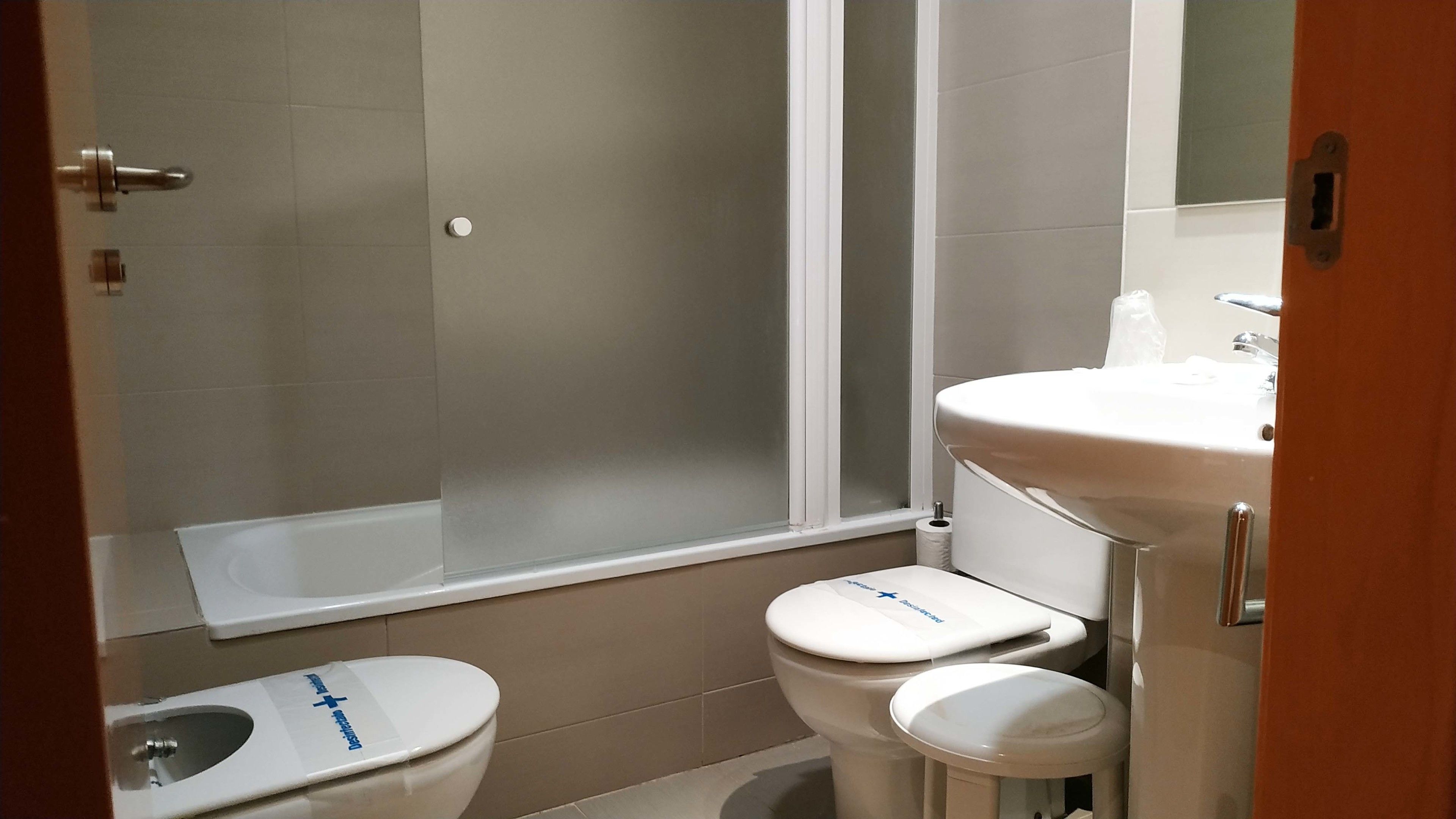 Une salle de bain équipée de toilettes, d’un bidet et d’un lavabo.