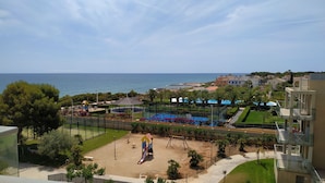 Uitzicht op de kust met een speeltuin, een strand en woongebouwen.