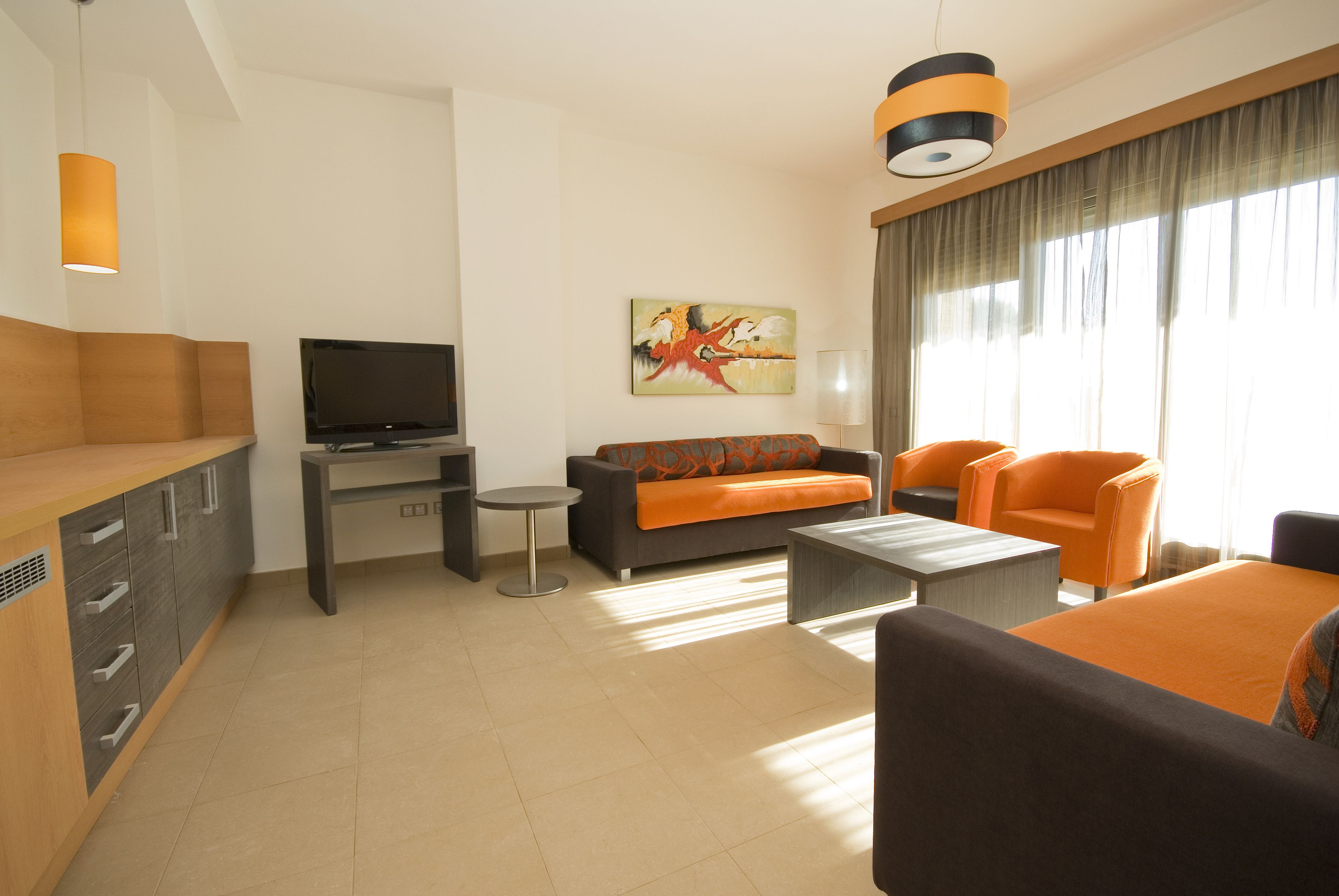 Una sala de estar moderna con un sofá, sillones, una mesa de centro, un televisor y un cuadro en la pared.
