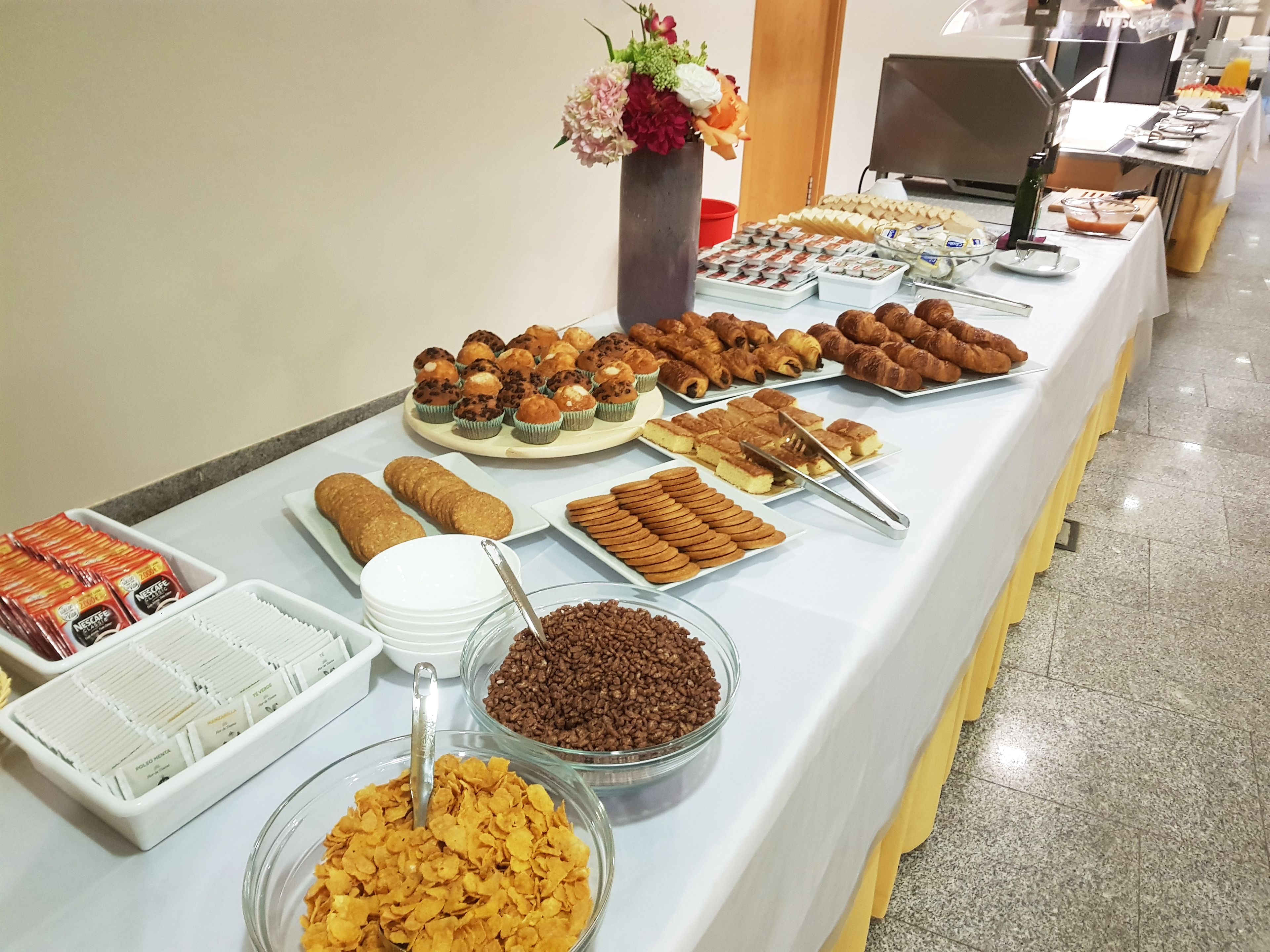 Une table de buffet proposant divers plats, notamment des pâtisseries, des biscuits et des céréales.