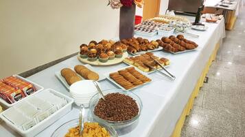 Une table de buffet proposant divers plats, notamment des pâtisseries, des biscuits et des céréales.
