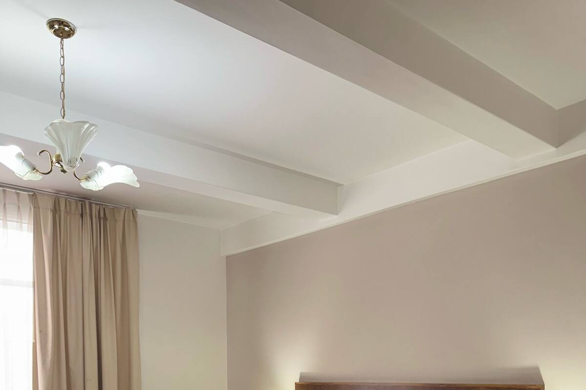 A hotel room with a large bed, wooden headboard, two bedside tables with lamps, a telephone, and a chandelier.