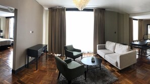 A hotel room with a sofa, two armchairs, a coffee table, a desk, and a chandelier. - Hotel Nutibara (Medellín)