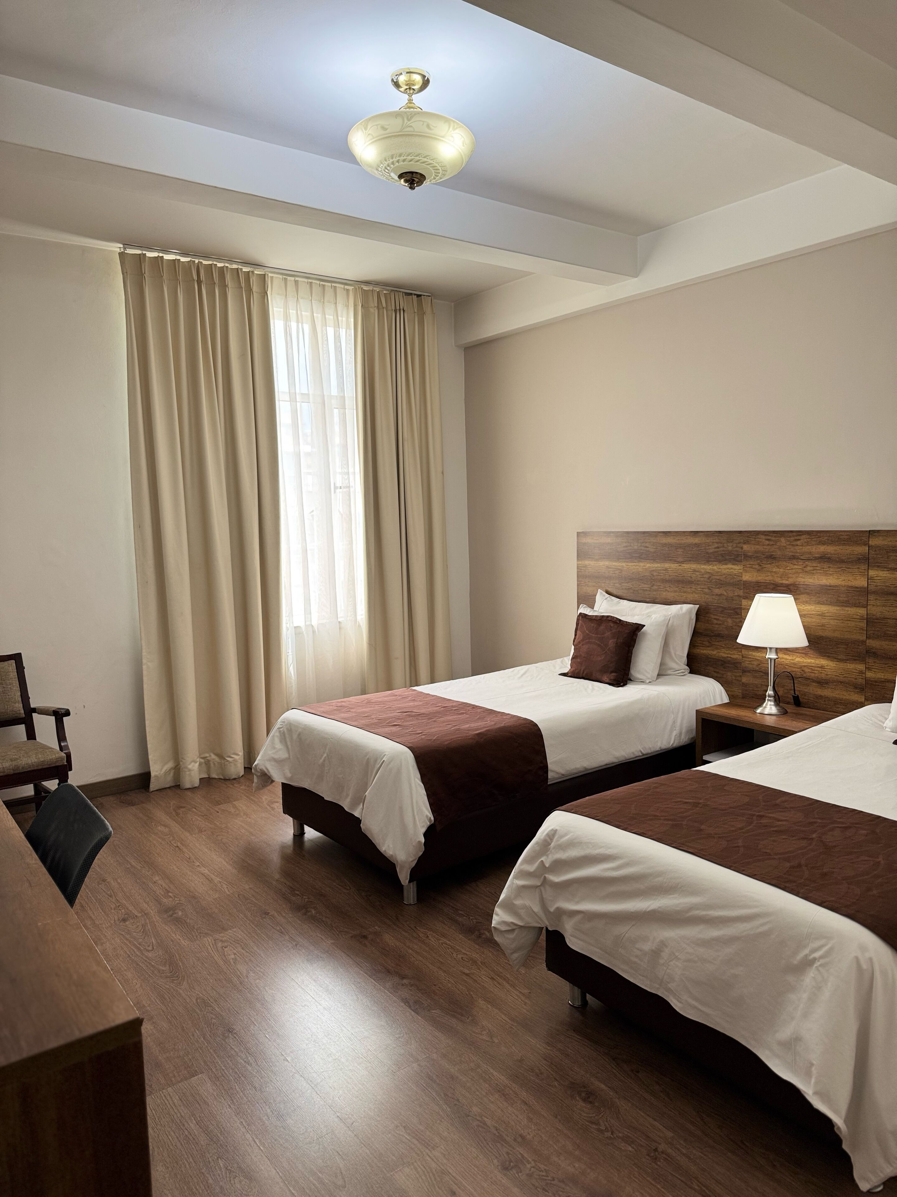 Een hotelkamer met twee bedden, een bureau en een stoel.