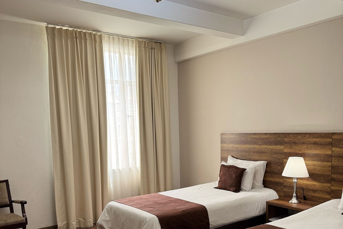 Une chambre d’hôtel avec deux lits, un bureau et une chaise.