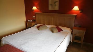 Una cama bien hecha con cabecera de madera, dos mesitas de noche con lámparas y un cuadro colgado en la pared.