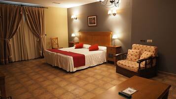 Ein Hotelzimmer mit Bett, Stuhl, Tisch und einer Chandelier.