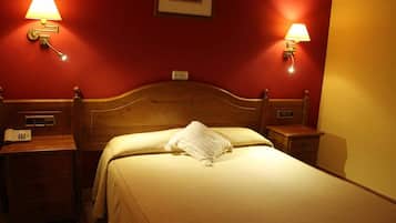 Een hotelkamer met een houten hoofdbord, twee nachtkastjes met lampen, een telefoon en een lijst met een afbeelding aan de muur.
