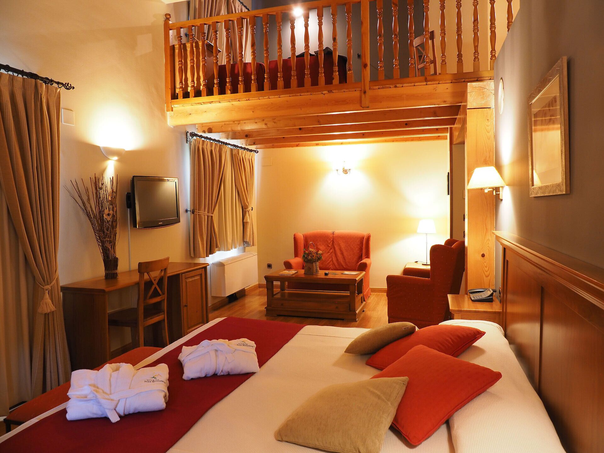 A hotel room with a bed, a desk, a chair, a TV, and a balcony.