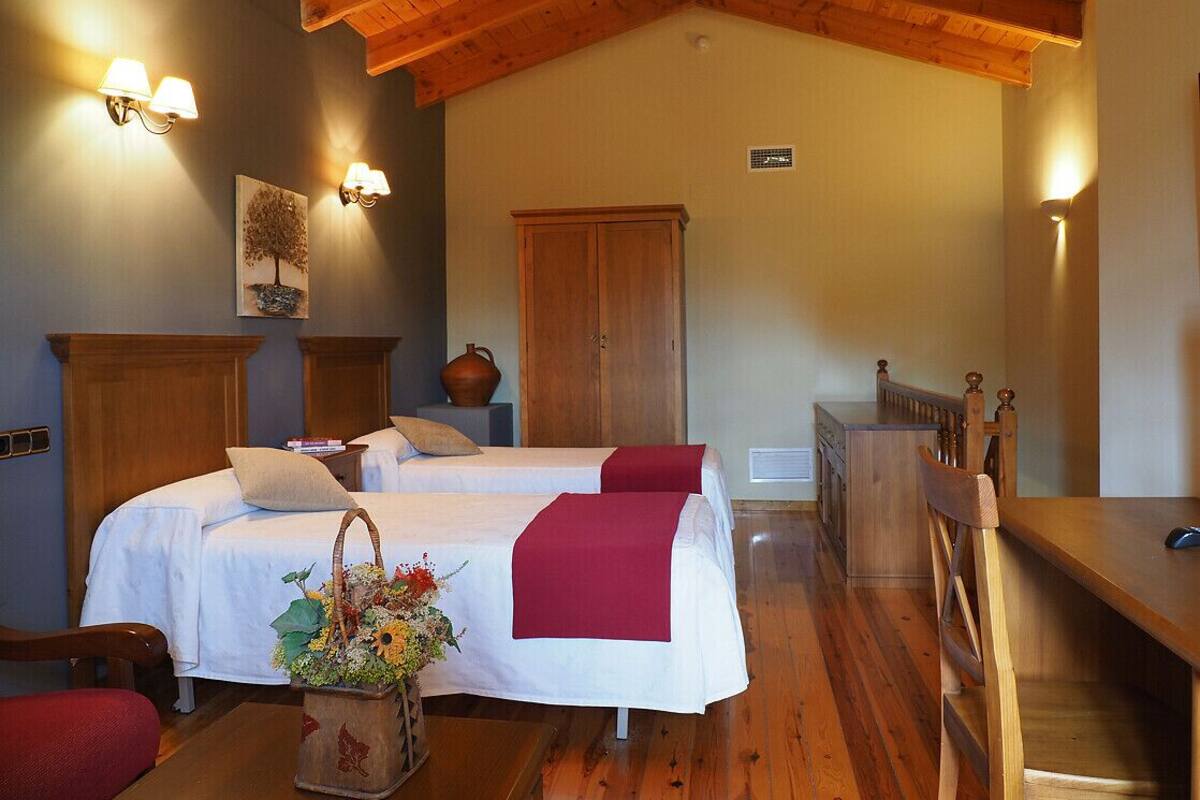 Una habitación con dos camas, muebles de madera e iluminación en la pared.