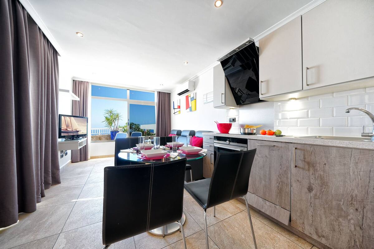 Una cocina moderna con comedor, ventanas amplias y vistas al exterior.
