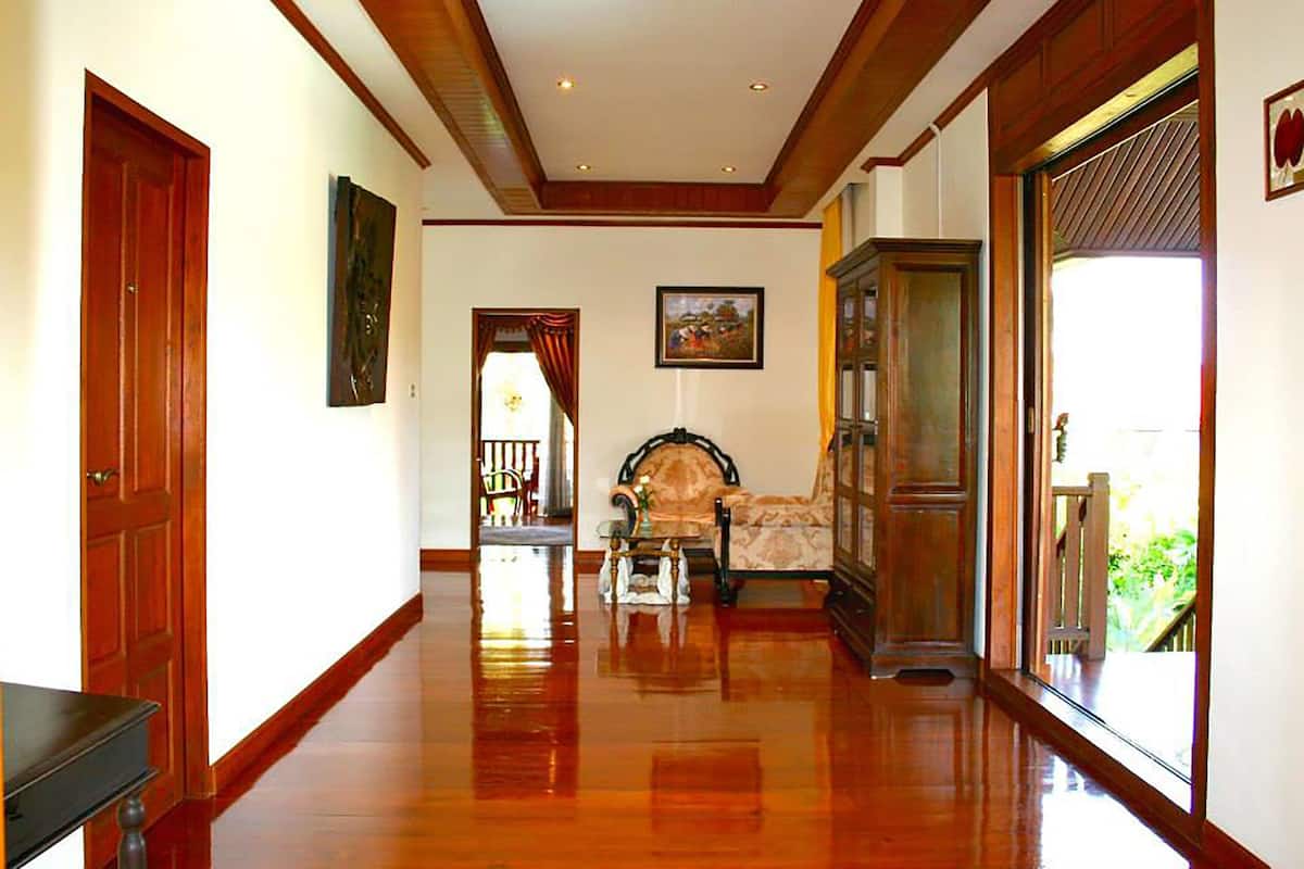 A hallway with wooden floors, a sofa, a cabinet, and a door.