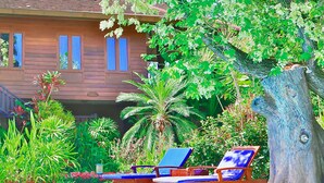 Una casa de fusta amb piscina, envoltada de vegetació exuberant i arbres.