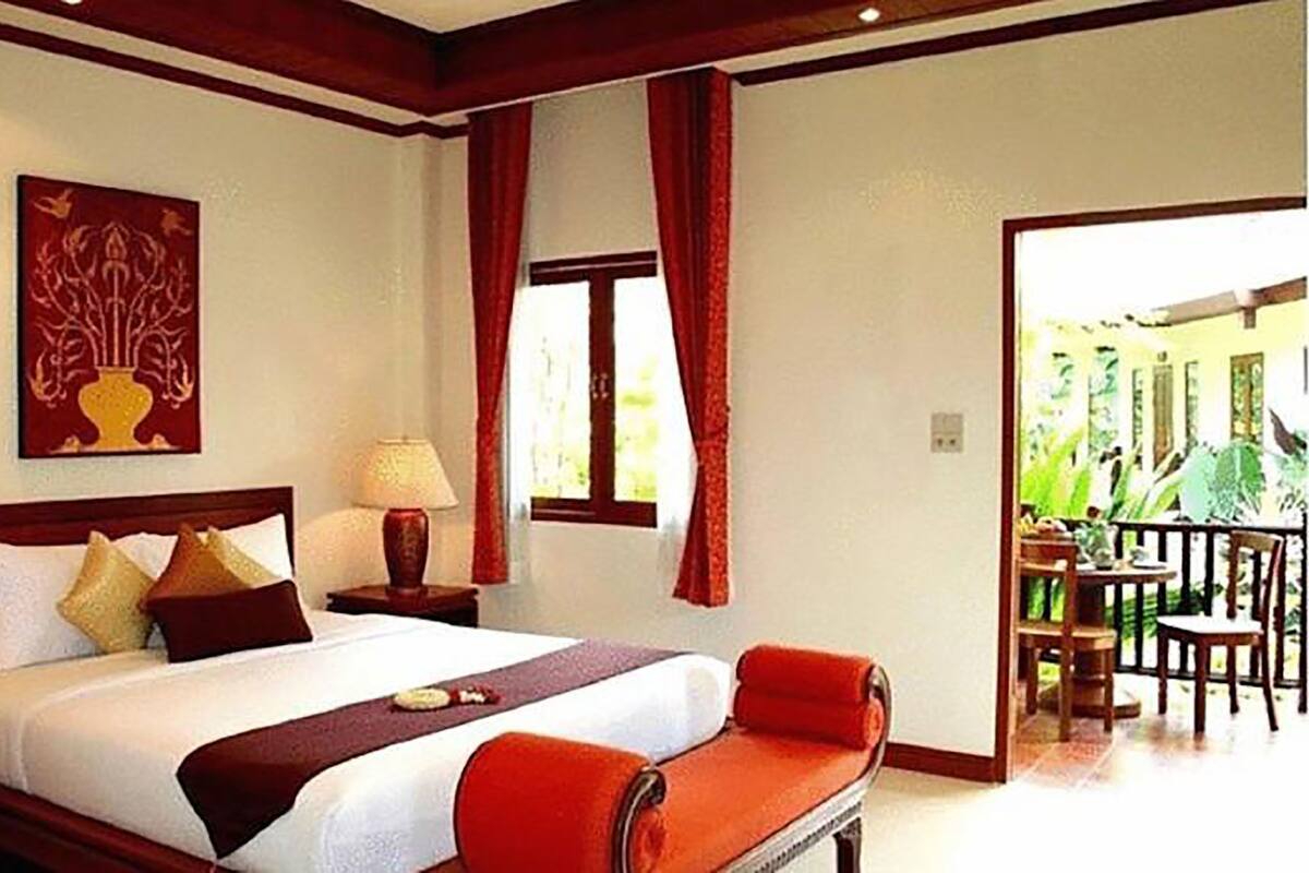 A hotel room with a large bed, two bedside tables with lamps, a painting on the wall, and a view of the outdoors.