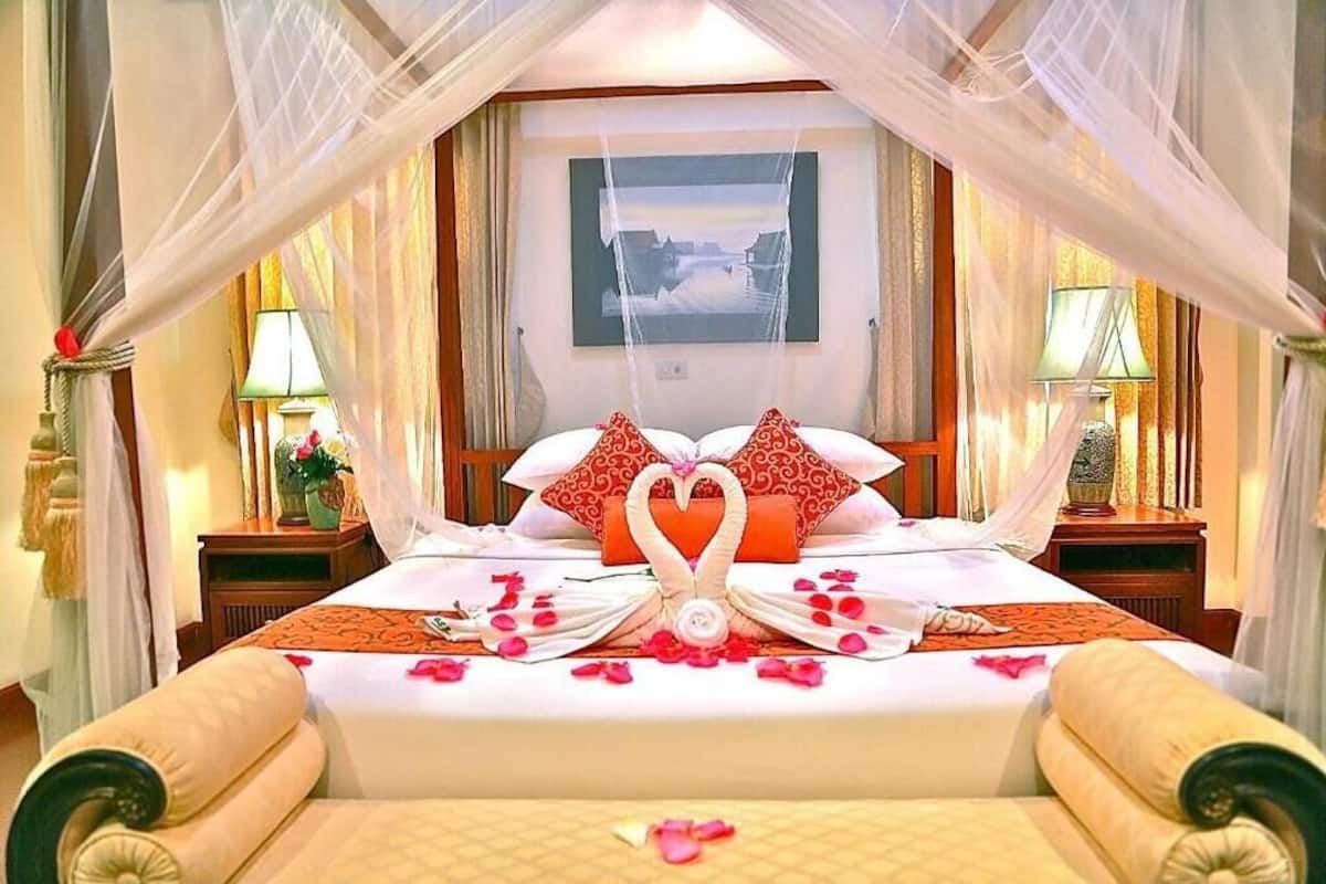 A bed with a canopy, two nightstands, a wall-mounted picture, and a decorative swan centerpiece.