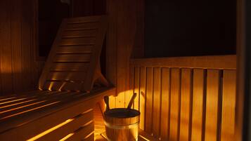 A sauna with wooden benches and a wooden bucket.