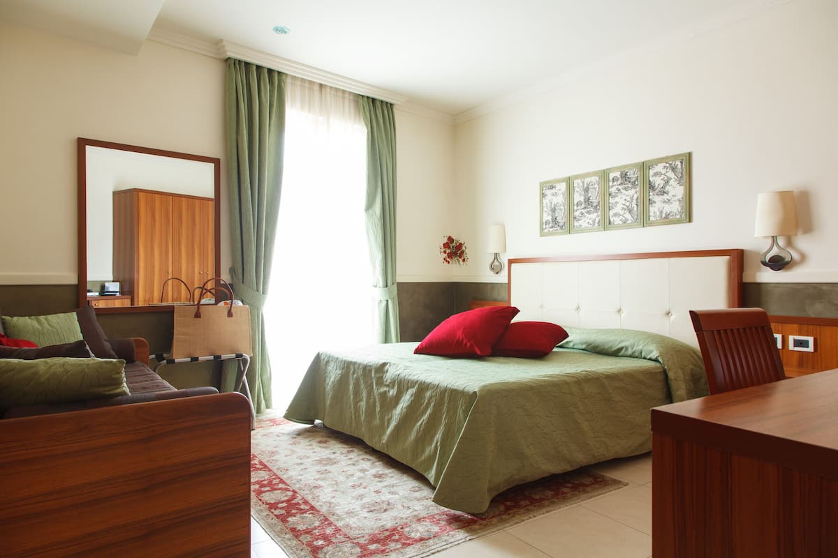 Une chambre à coucher comprenant un lit, un bureau, une chaise, une commode et un miroir.