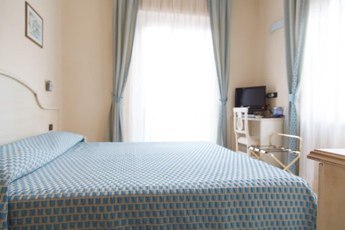 Une chambre d’hôtel avec un lit, un bureau équipé d’un ordinateur et un téléviseur.