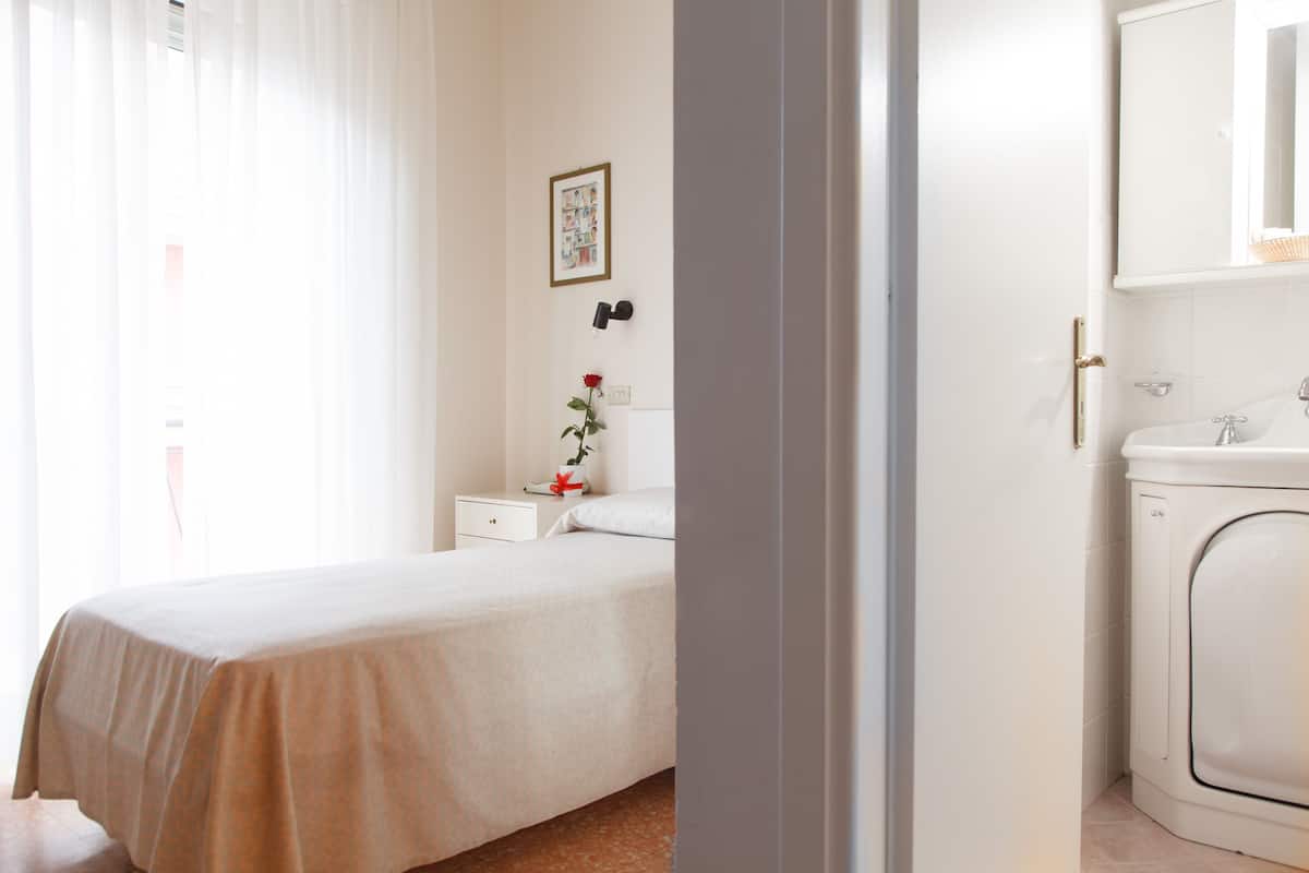 Une chambre à coucher comprenant un lit, une table de chevet, une commode, un miroir et un lave-linge.