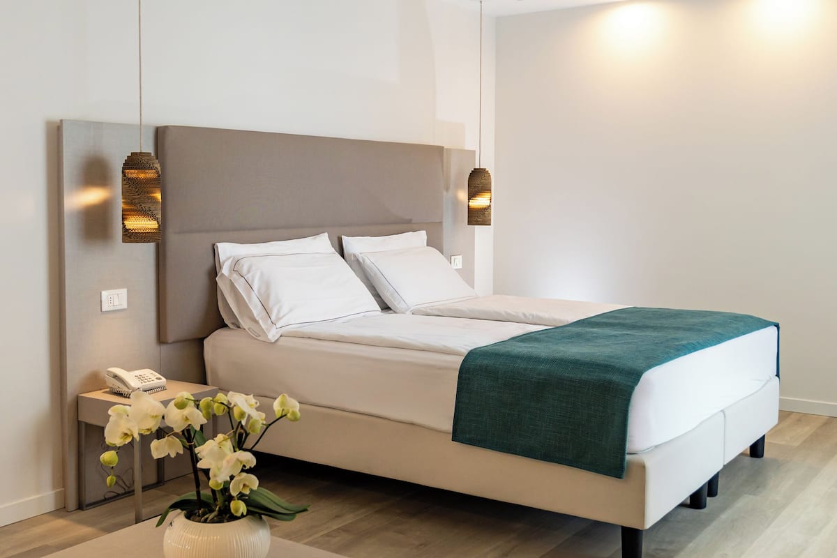 Une chambre à coucher moderne avec un lit, une table de chevet et un vase de fleurs.