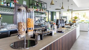 Zona de bufé con varios dispensadores de comida, área de bar con botellas y vasos, y mostrador con diversas opciones de alimentos.