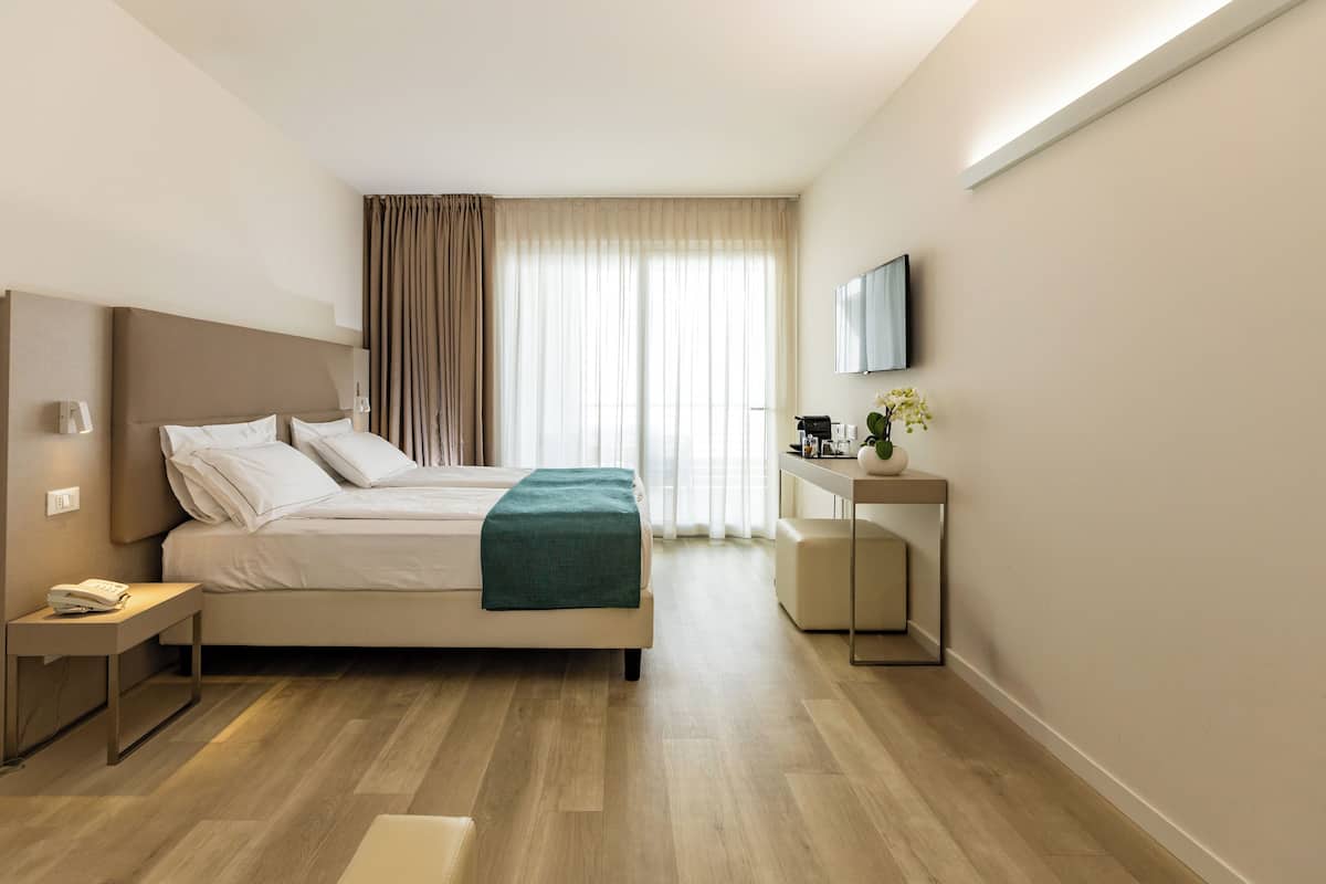 Une chambre d’hôtel moderne équipée d’un lit, d’une table de chevet et d’un petit bureau avec un miroir.