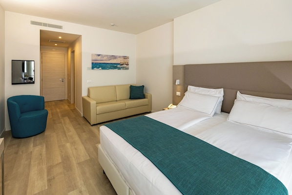 Una habitación de hotel con una cama, un sofá, una silla, un cuadro y una puerta.