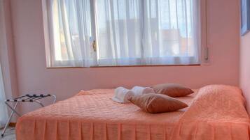 Una habitación de hotel con cama, almohadas, una mesa y una silla.