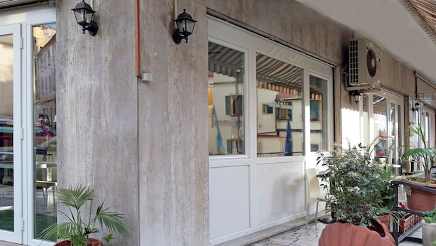 L’extérieur d’un hôtel avec un bar, des tables et des chaises en plein air, et des plantes en pot.