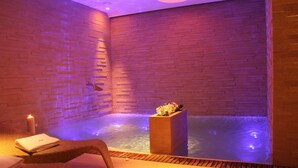 Ein Spa-Raum mit Backsteinwand, einem kleinen Pool und einer Blumenkomposition.
