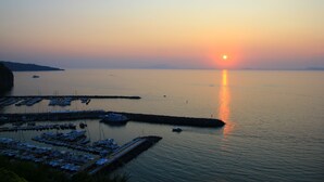 Ein Yachthafen mit anlegenden Booten, ruhigem Wasser und einem Sonnenuntergang im Hintergrund.