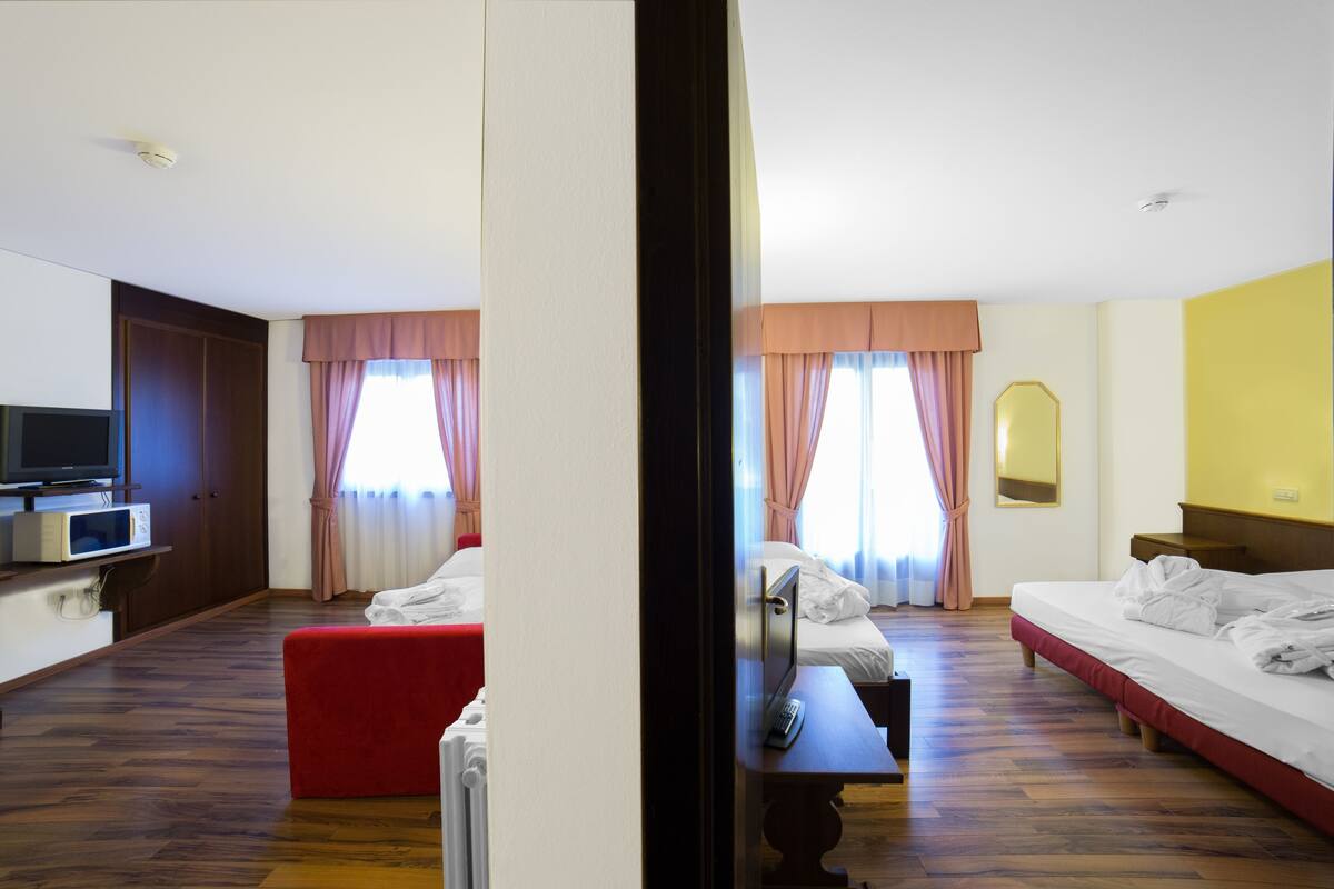 Ein Hotelzimmer mit einem Bett, einem roten Hocker, einem Fernseher und einem Nachttisch.
