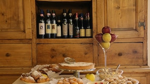 A wooden cabinet with wine bottles and a dessert display. - Hotel Baita Clementi (Bormio)