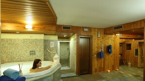 A wooden interior with a bathtub, a shower, and a door leading to another room. - Hotel Baita Clementi (Bormio)