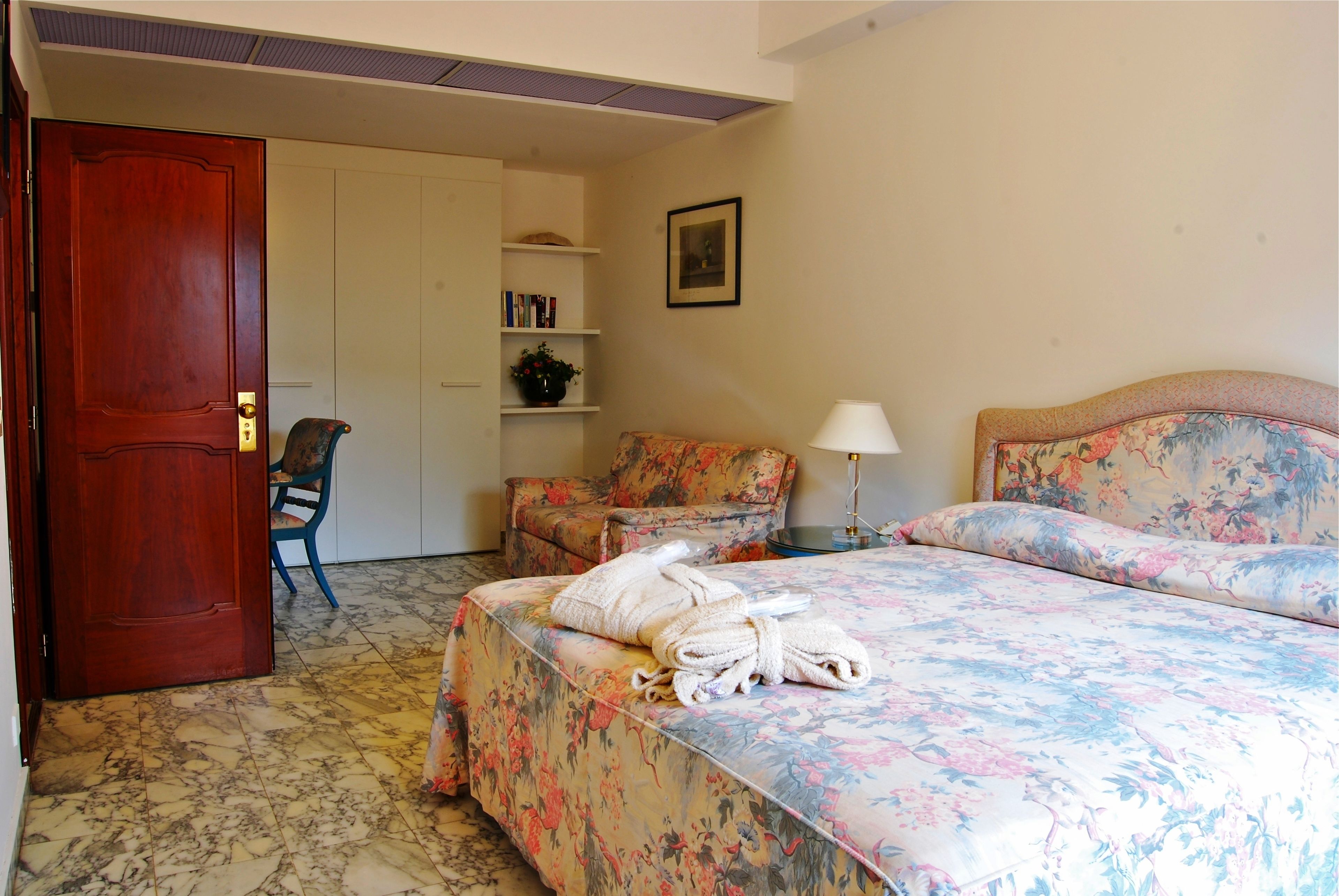 Una camera d'albergo con un letto, una sedia, una scrivania e una porta.