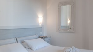A hotel room with a bed, pillows, a bedside table, a lamp, and a mirror. - Hotel President (Forte dei Marmi)