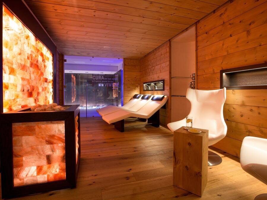 A spa room with wooden walls, two massage tables, and a wooden side table.