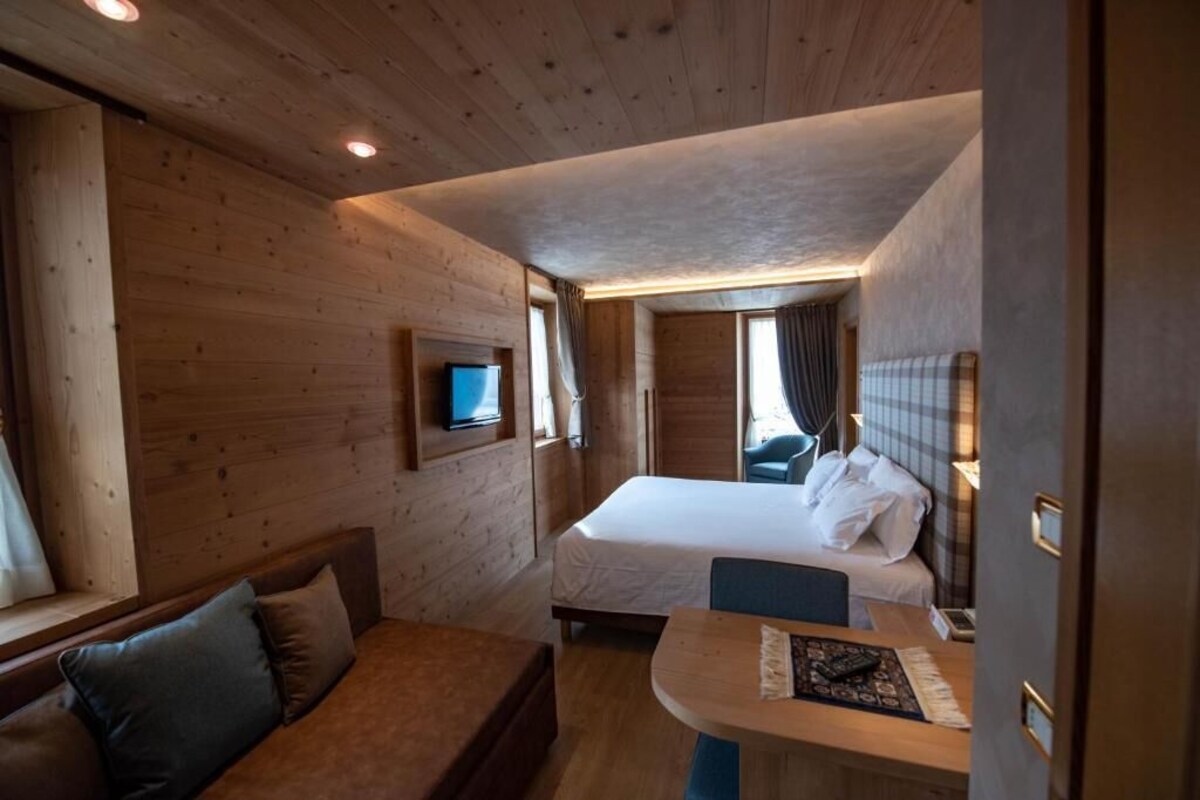 Une pièce de cabane en bois comprenant un lit, un canapé, une table et un téléviseur.