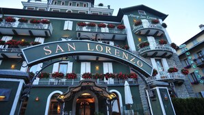 The exterior of the San Lorenzo Hotel with a prominent archway, multiple balconies with flower boxes, and a classic European architectural style. - San Lorenzo (Bormio)