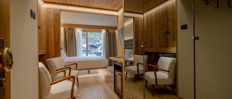A modern room with wooden flooring, a sofa, chairs, a small table, and a window with curtains.