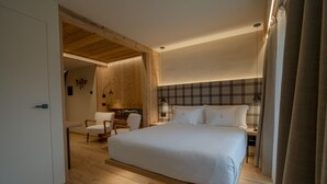 A bedroom with a large bed, wooden flooring, a checkered headboard, and a desk with a chair. - San Lorenzo (Bormio)