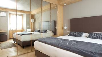 Una camera da letto moderna con due letti, travi in legno e un ampio specchio.