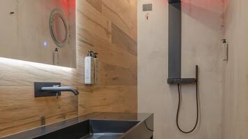 A modern bathroom with a wooden vanity, a large mirror, and a shower area.