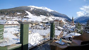 A terrace with outdoor seating, overlooking a snow-covered town and mountains. - San Lorenzo (Bormio)