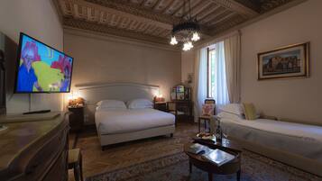 A hotel room with a large bed, a sofa, a television, a desk, and a patterned rug.