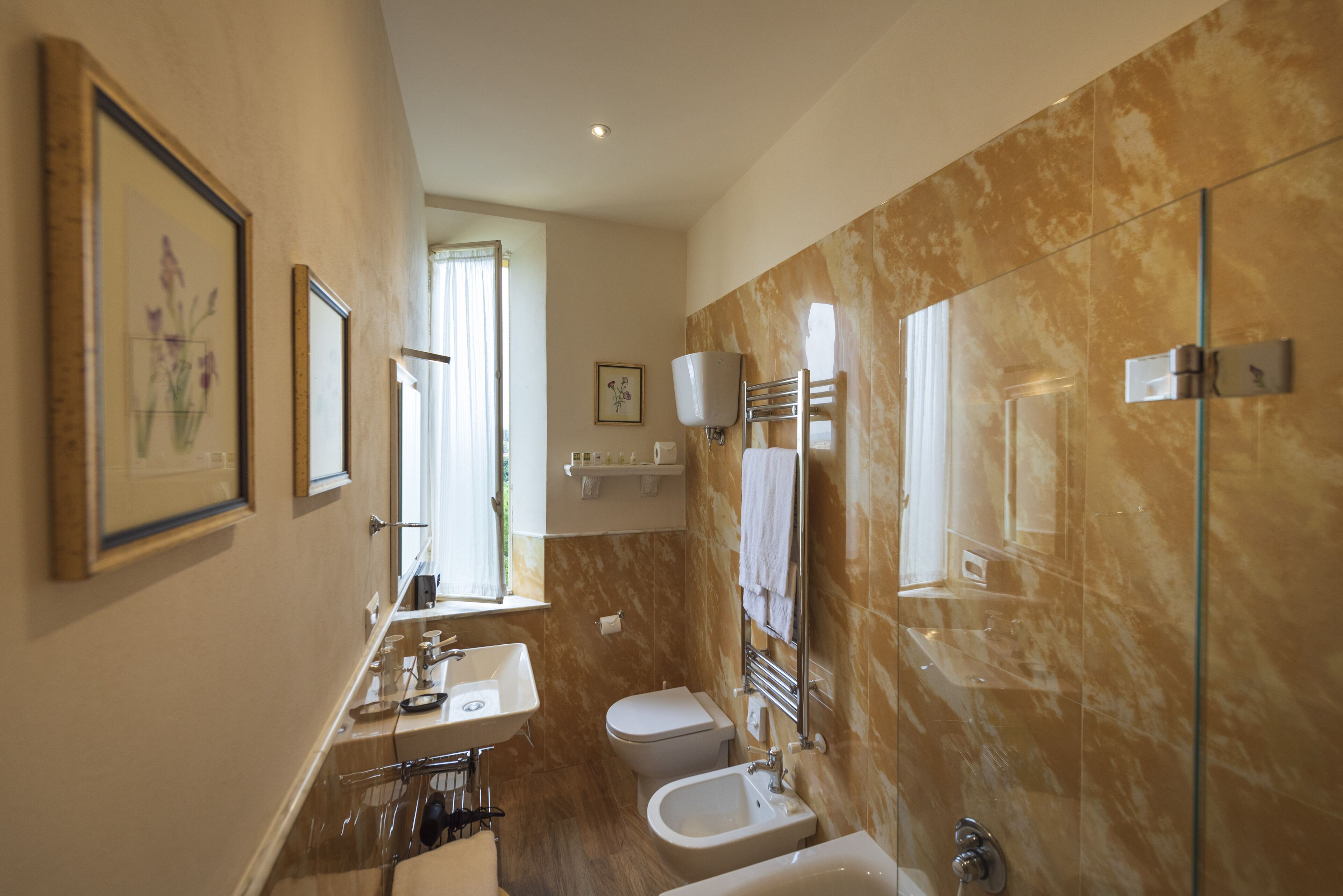 Un bagno moderno con lavandino, servizi igienici, bidet e doccia con pareti in vetro.