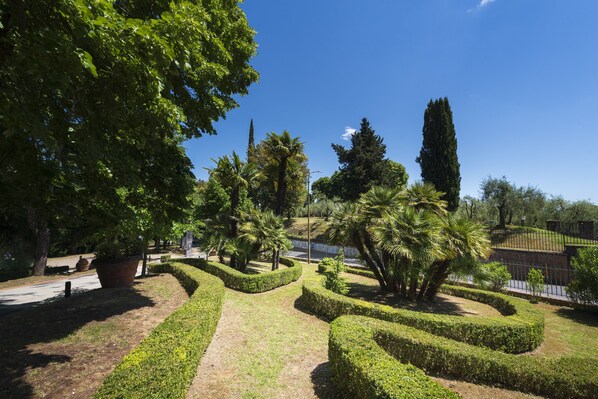 Un jardín arbolado con diversas especies arbóreas y setos cuidadosamente recortados.