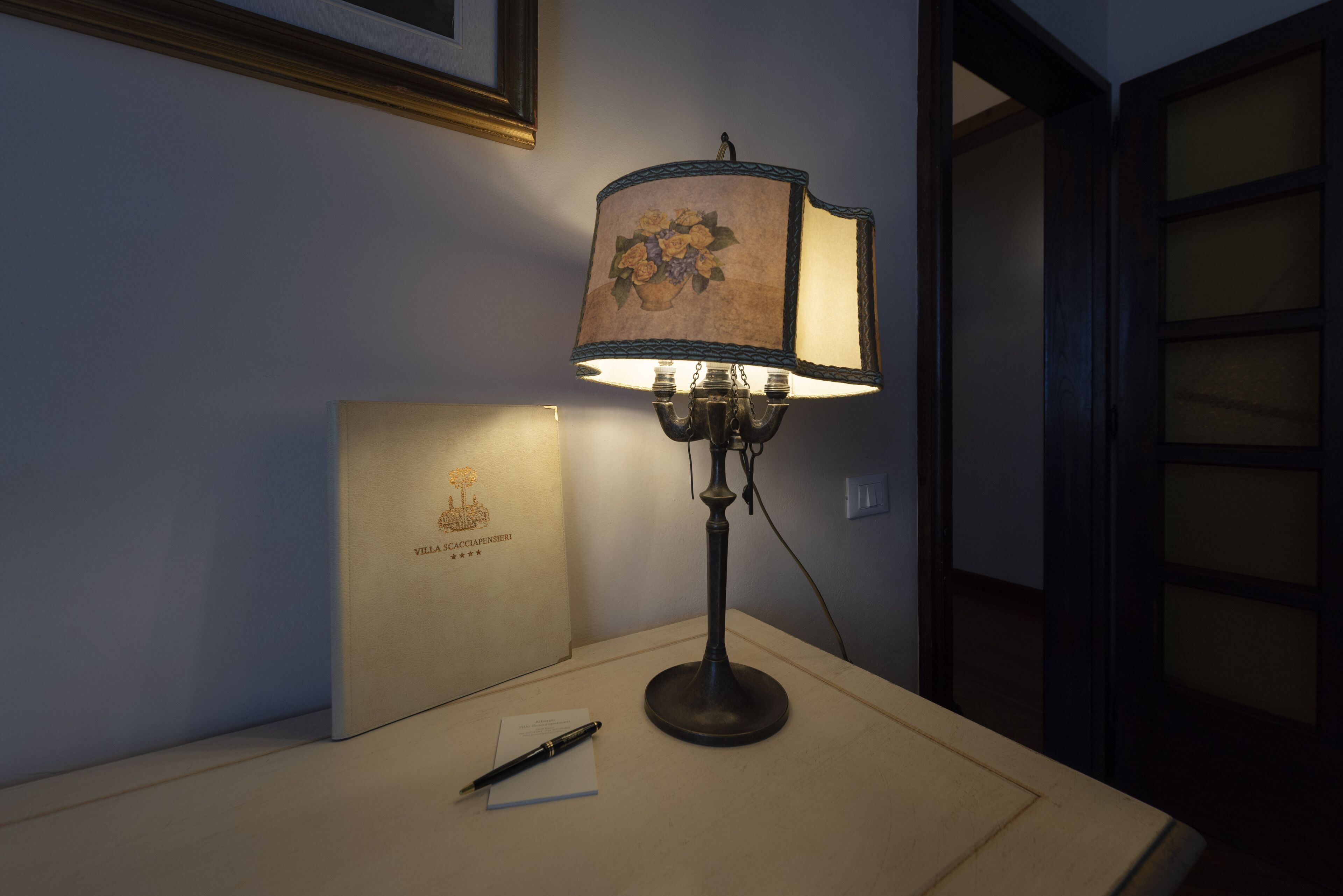 A desk with a lamp, a pen, and a notepad.