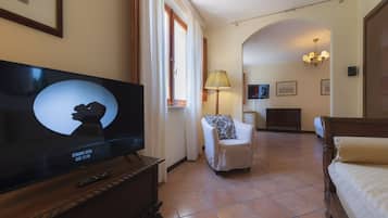 Ein Hotelzimmer mit Fernseher, einem Sessel, einem Bett, einer Lampe und einem Holzschrank.